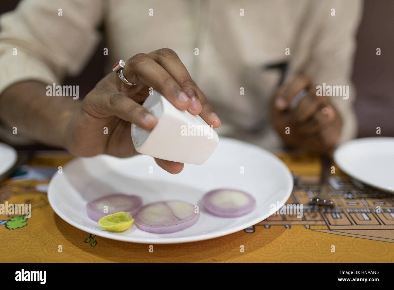 HYDERABAD, INDE - FÉVRIER 10,2017.un client saupoudre de sel sur les rondelles d'oignons et un soupçon de lime dans un restaurant local à Hyderabad, Inde Banque D'Images