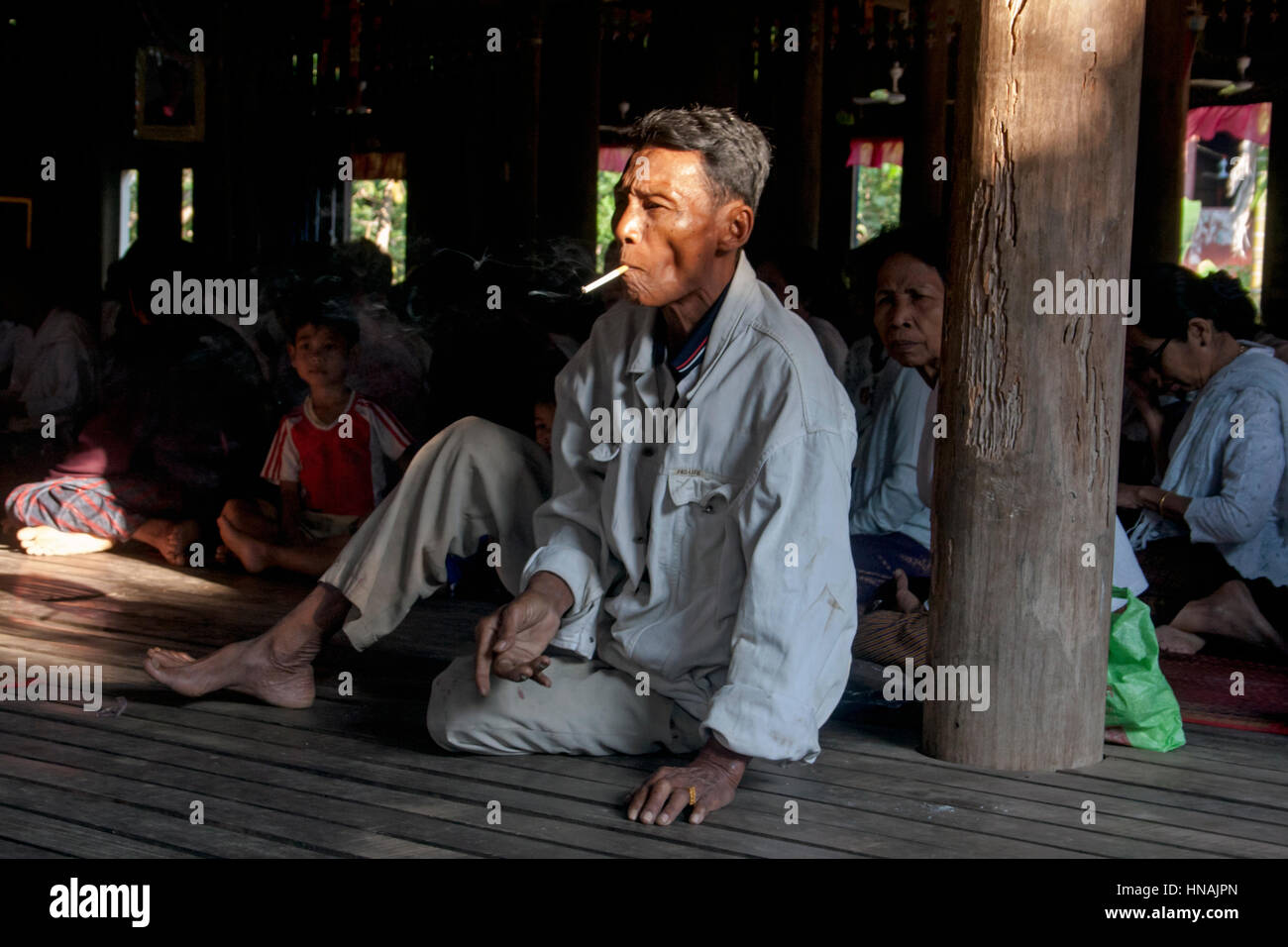 Un bouddhiste laïque est de fumer une cigarette à l'intérieur une pagode au cours d'une cérémonie à Chork, village au Cambodge. Banque D'Images