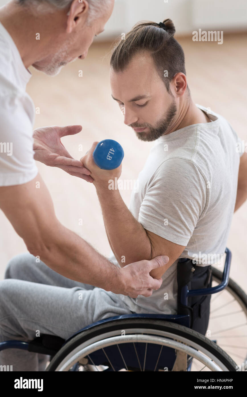 Mobilité concentré man exercising avec son entraîneur dans la salle de sport Banque D'Images