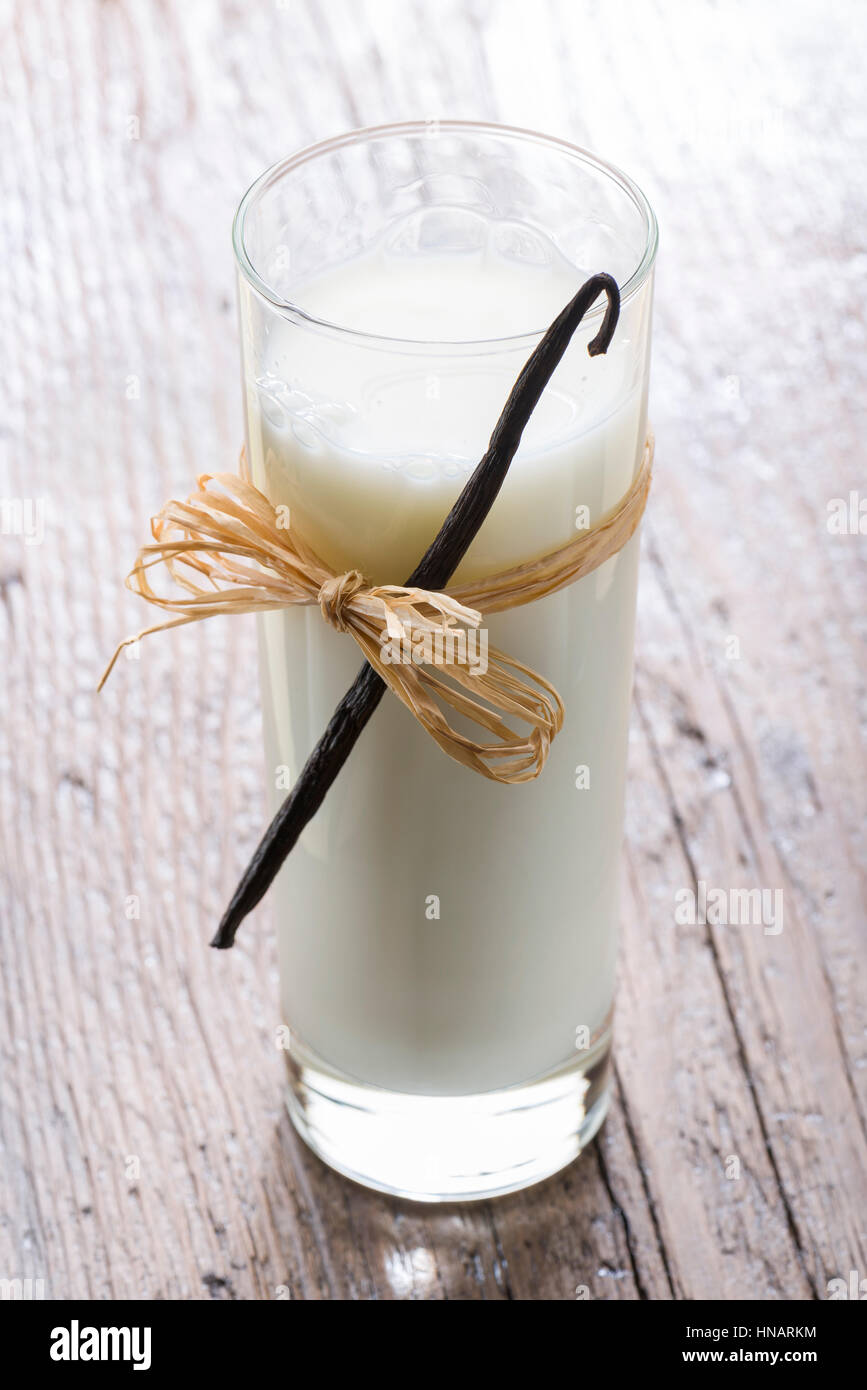 Verre de lait avec le bâton de vanille sur table en bois Banque D'Images