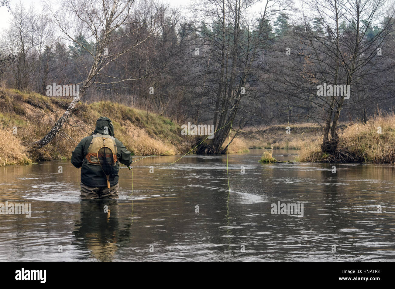 Pêcheur la pêche sur une petite rivière de printemps. La pêche à la mouche. Banque D'Images