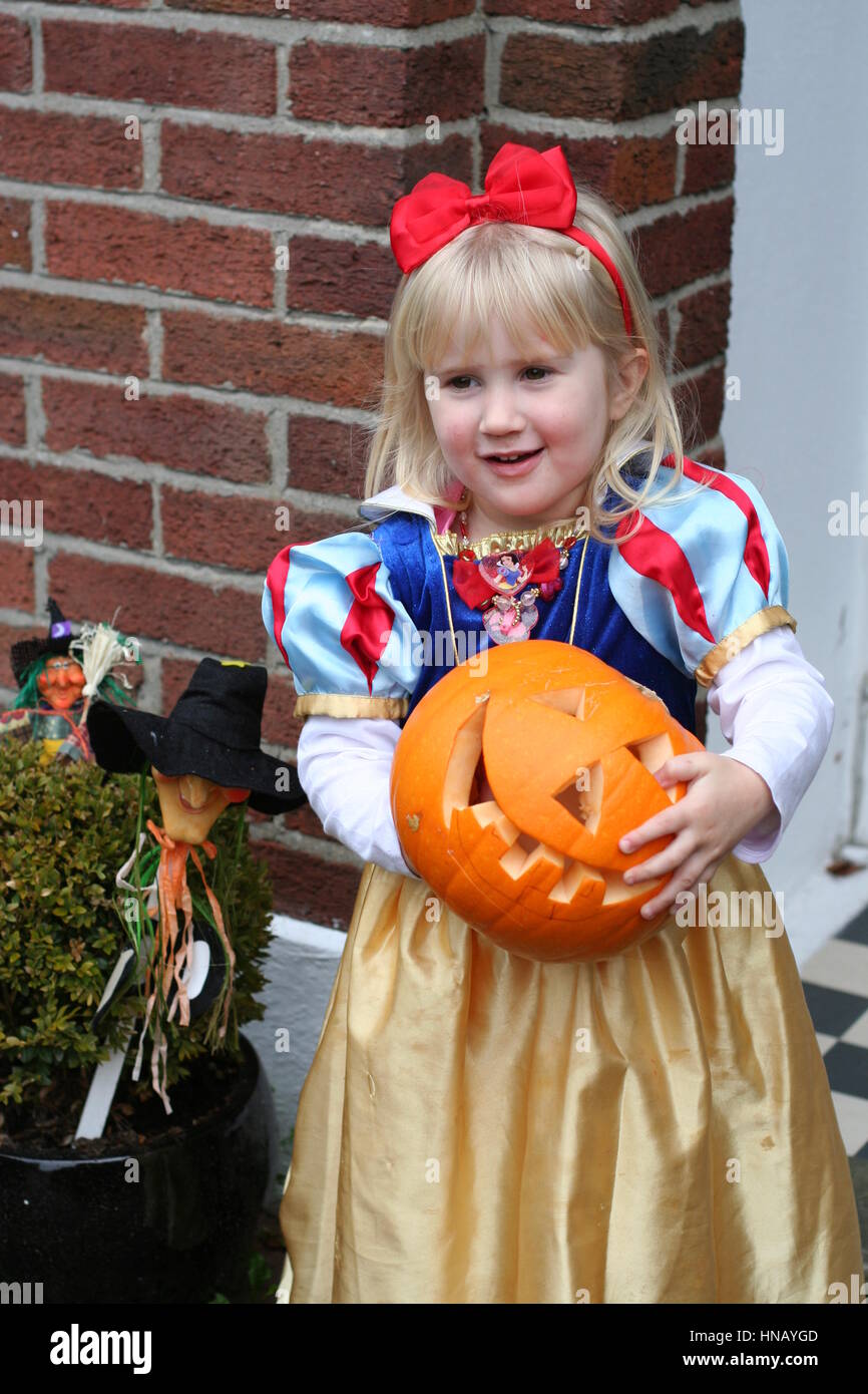 La petite blonde girl holding une lourde citrouille sculptée portant un  costume princesse Blanche Neige à l'Halloween, Trick ou traiter l'innocence  de la joie Photo Stock - Alamy