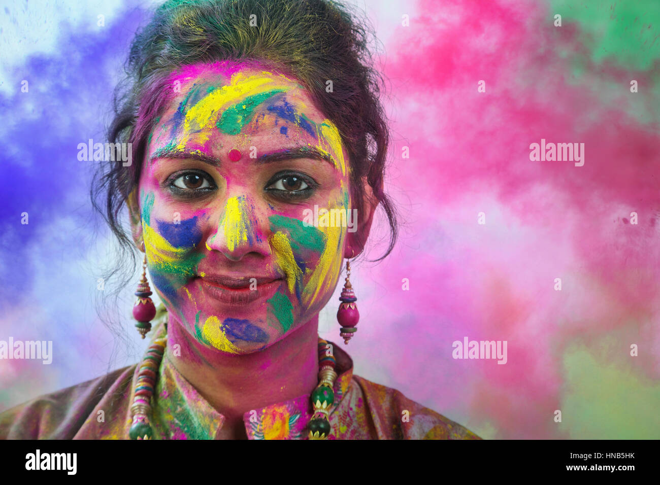 Portrait de jeune femme indienne avec différentes couleurs de Holi festival couleur face au cours de Banque D'Images