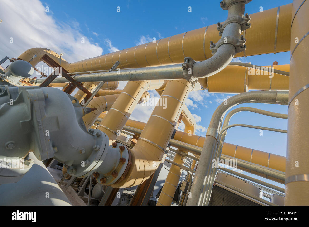 Tuyaux industriels jaune avec ciel bleu Banque D'Images