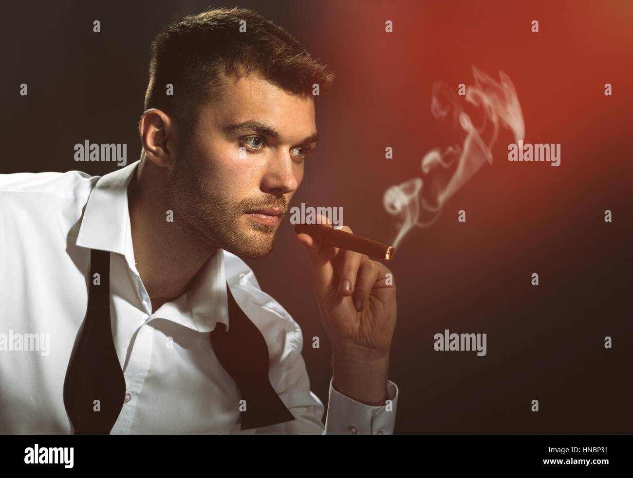Bel homme avec papillon fumer un cigare Banque D'Images