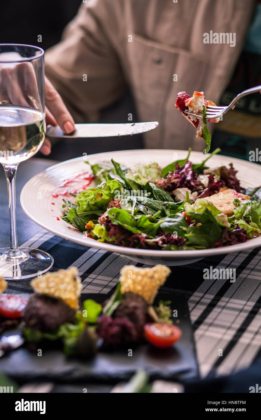 Fromage de chèvre Woman et salade de fraises avec un verre de vin blanc Banque D'Images