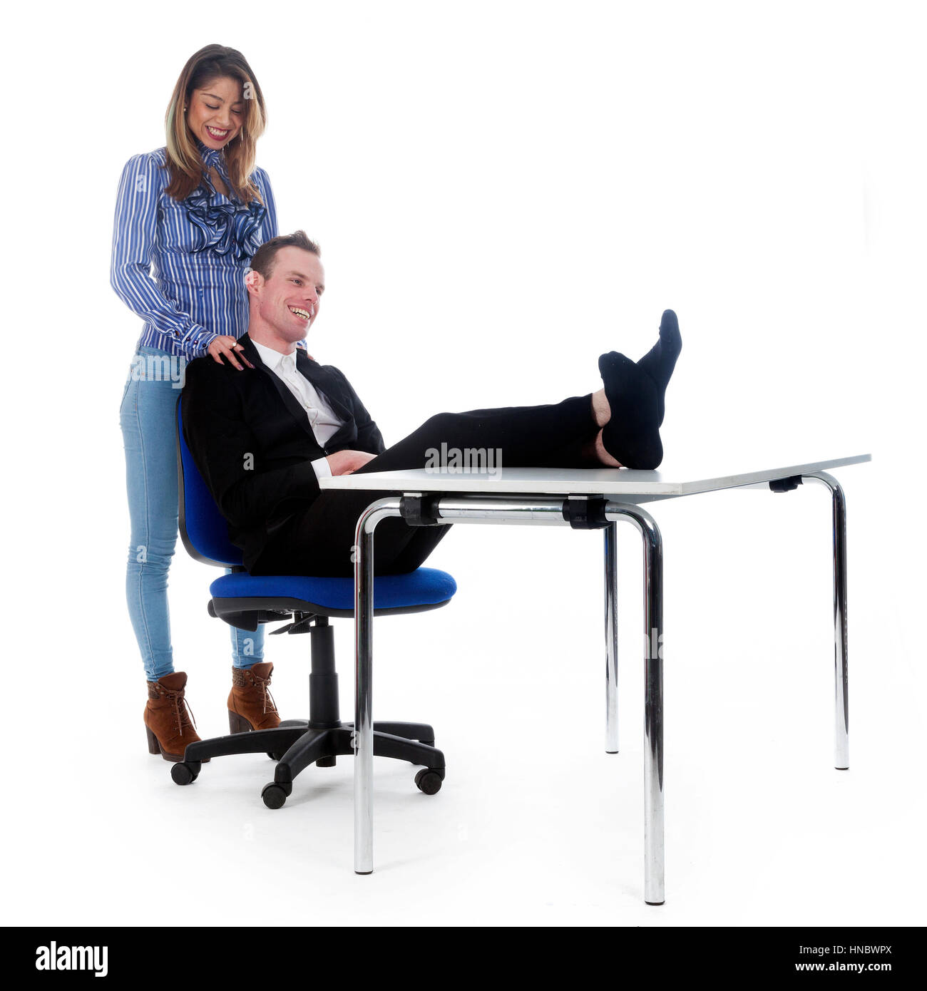 Jeune femme donne patron massage et il a ses pieds sur la table en studio against white background Banque D'Images