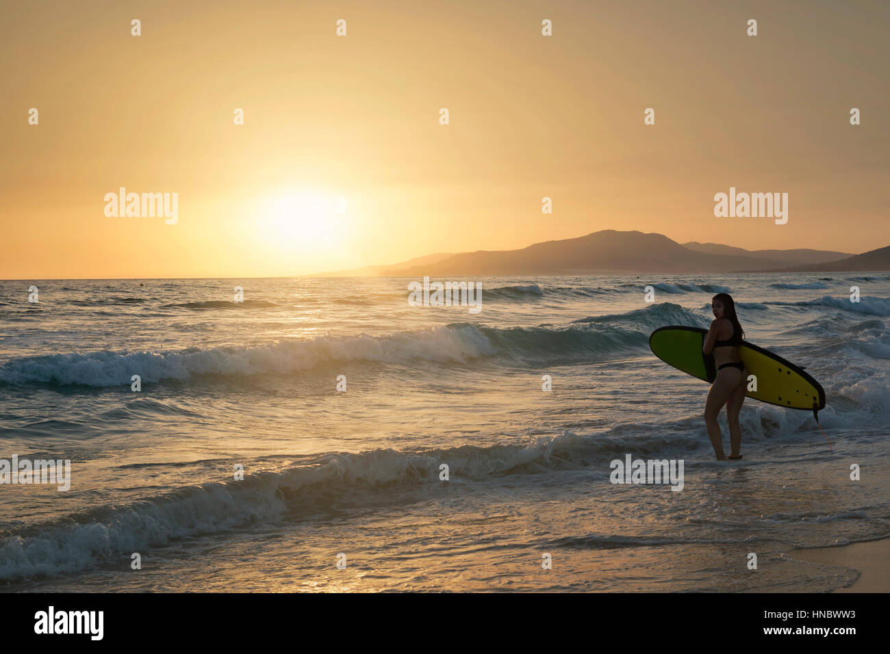 Silhouette d'une femme portant un surf, la plage de Los Lances, Tarifa, Cadix, Andalousie, Espagne Banque D'Images