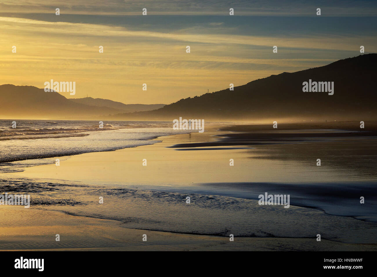 Silhouette d'une personne qui marche le long de plage au coucher du soleil, la plage de Los Lances, Tarifa, Cadix, Andalousie, Espagne Banque D'Images