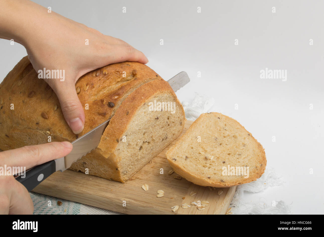 Mains de trancher le pain de blé entier avec couteau à pain Banque D'Images