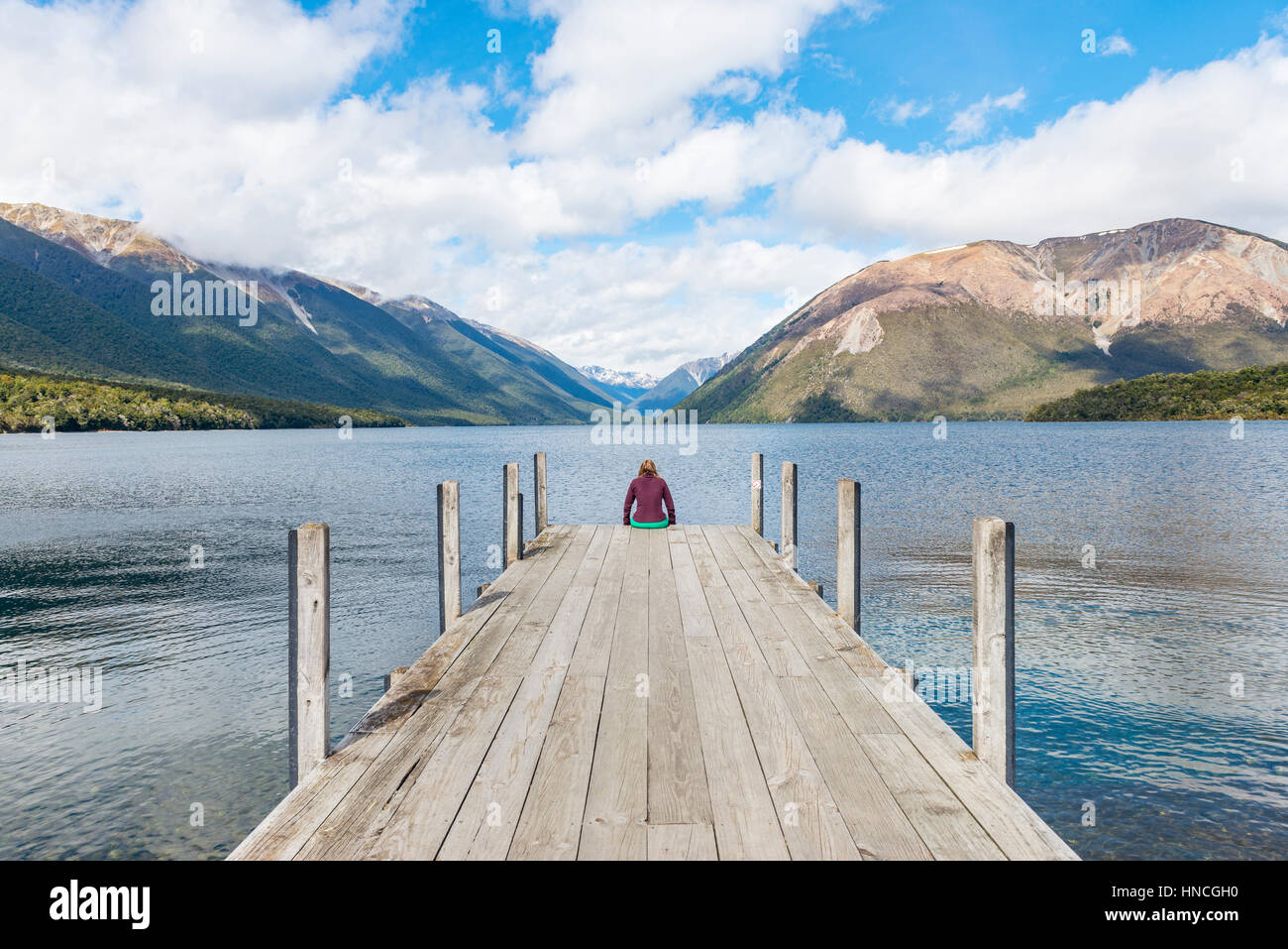 Femme assise sur un quai, vue du lac Rotoiti, Nelson Lakes National Park, district de Tasmanie, Southland, Nouvelle-Zélande Banque D'Images