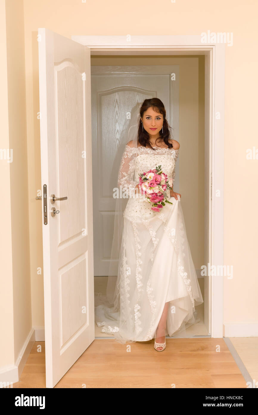 Jolie jeune femme entre dans la chambre dans sa robe de mariage traditionnelle Banque D'Images