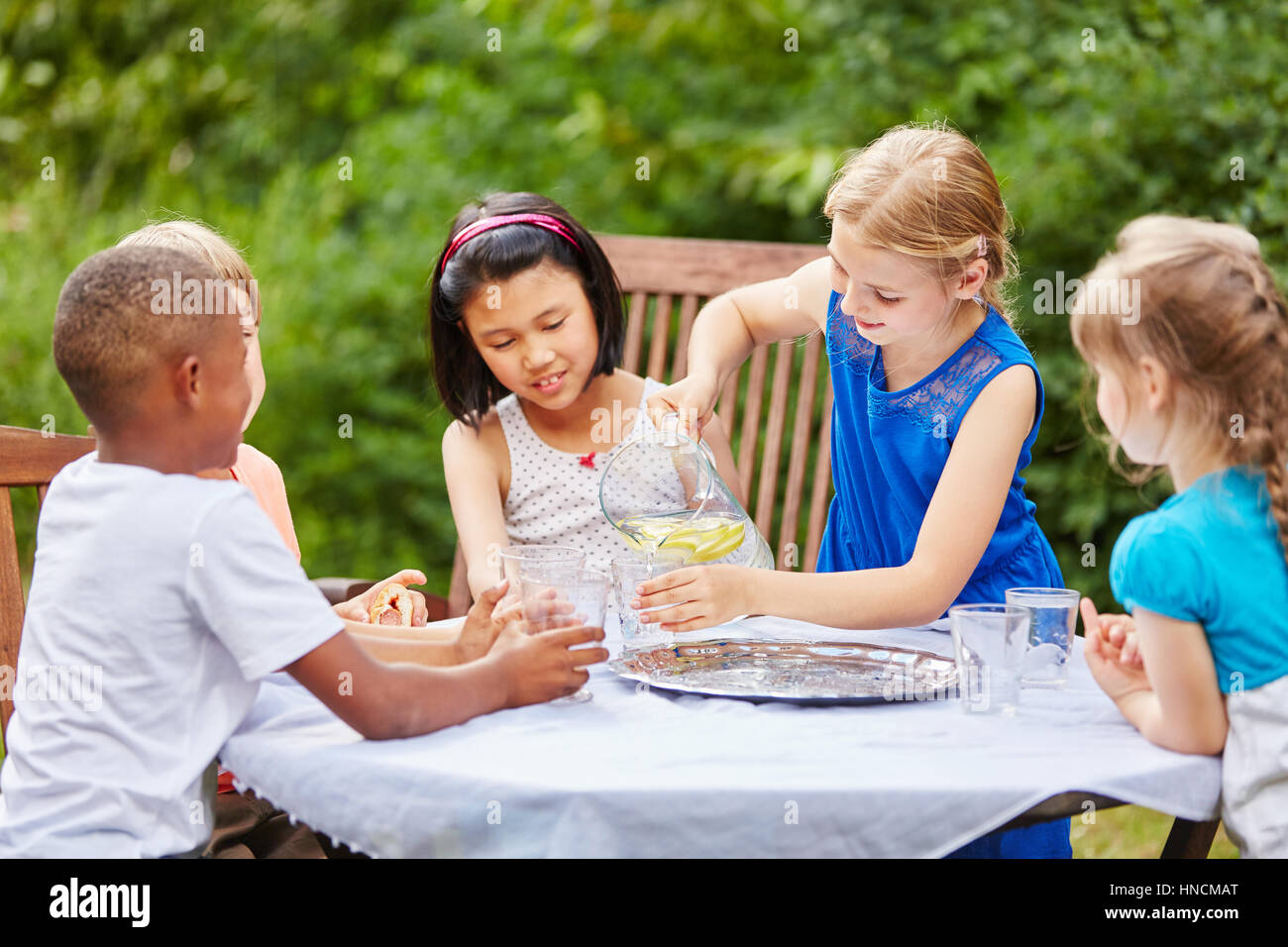 L'Interracial groupe d'enfants comme des amis boire de l'eau at party Banque D'Images