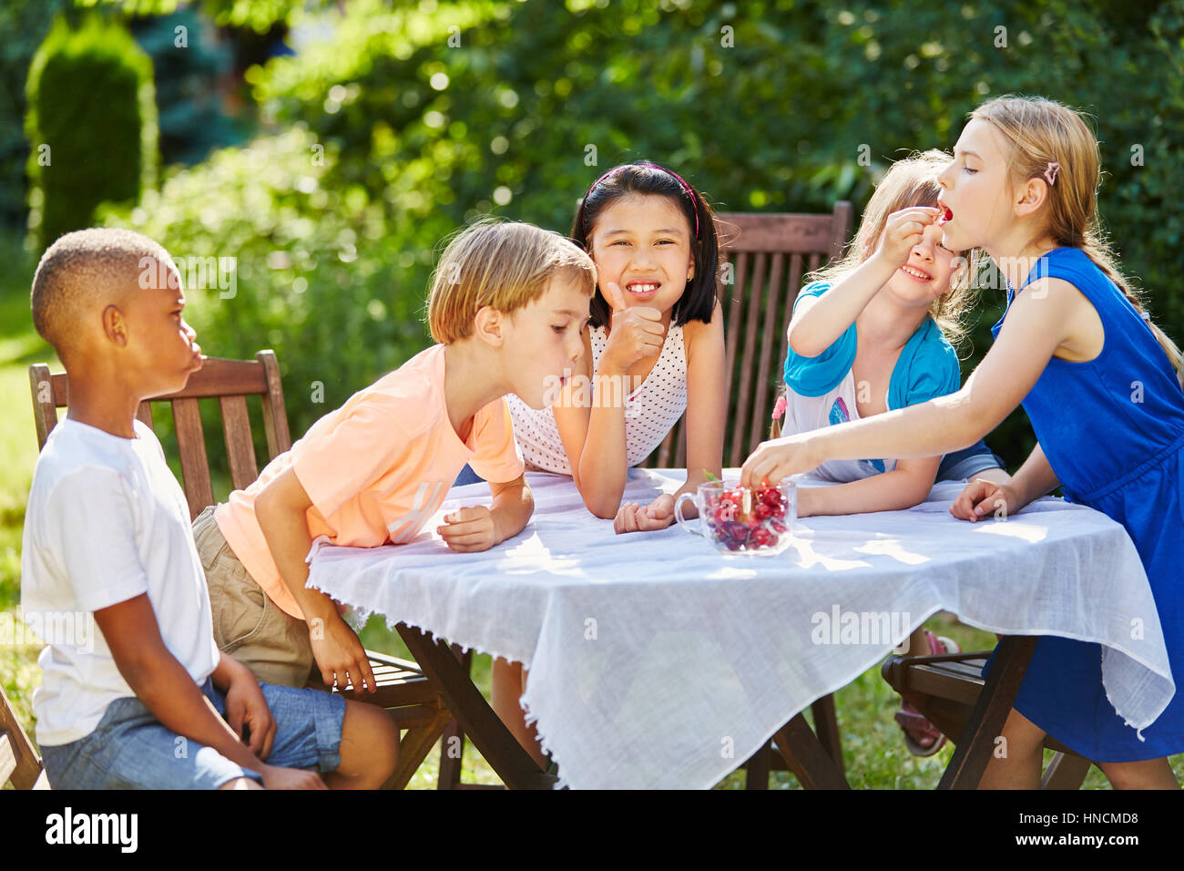 Groupe d'enfants en bonne santé manger des fruits comme les cerises au jardin en été et s'amuser Banque D'Images