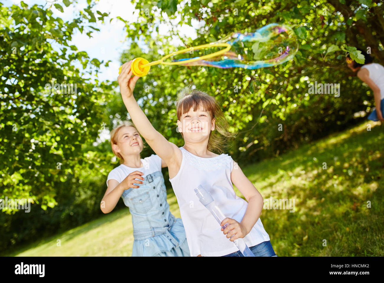 Happy active les filles jouant avec des bulles de savon en été dans le parc Banque D'Images