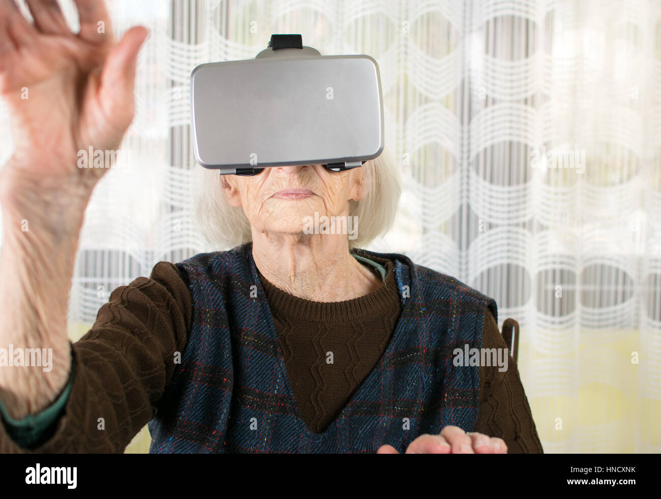 Senior woman en utilisant des lunettes de réalité virtuelle à la maison Banque D'Images