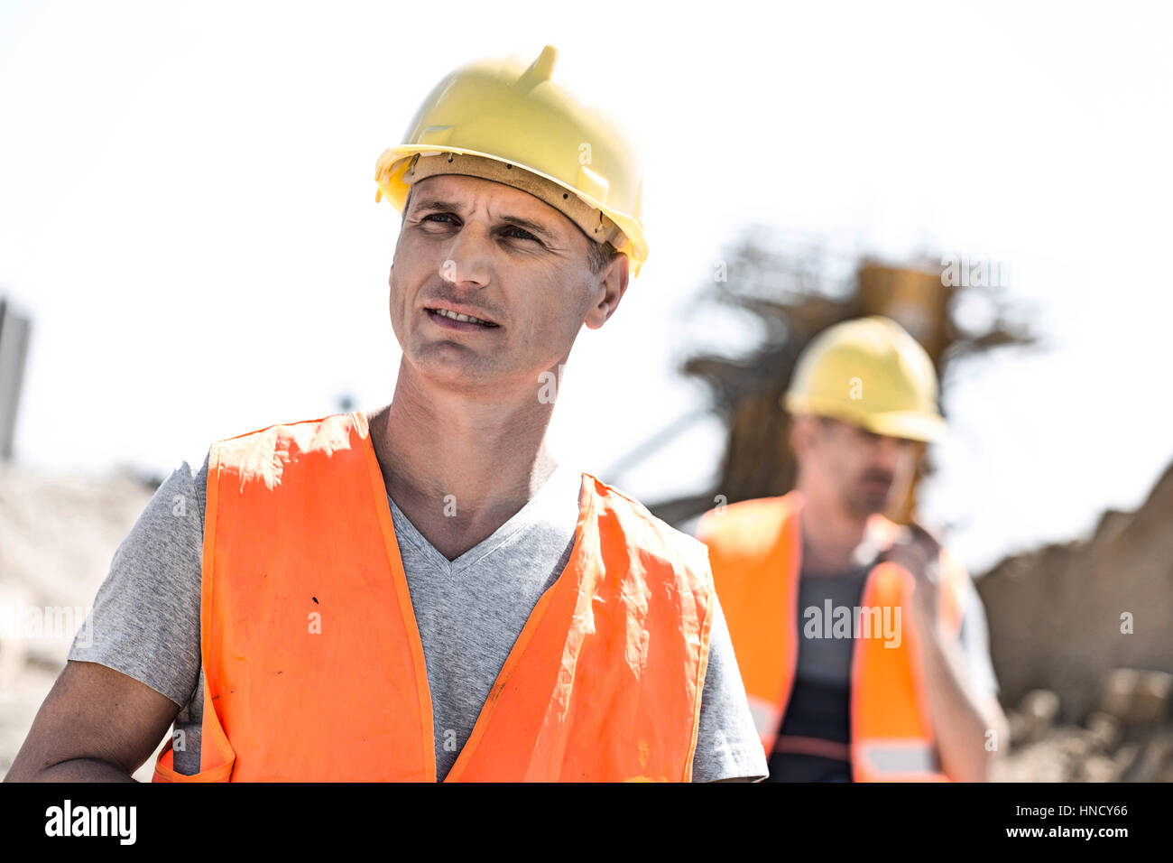 Travailleur homme at construction site avec collègue debout en arrière-plan Banque D'Images