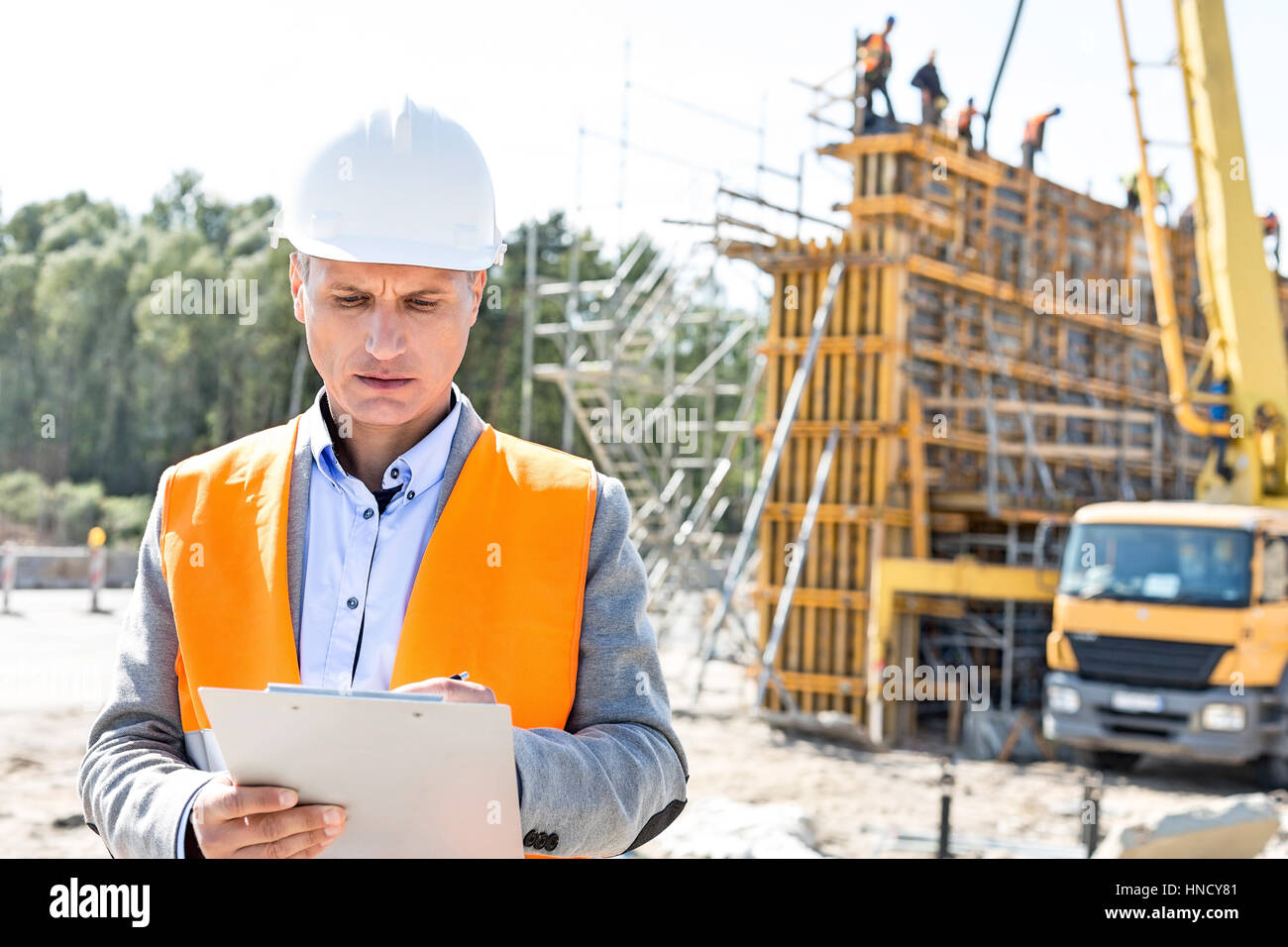 Supervisor writing on clipboard at construction site Banque D'Images