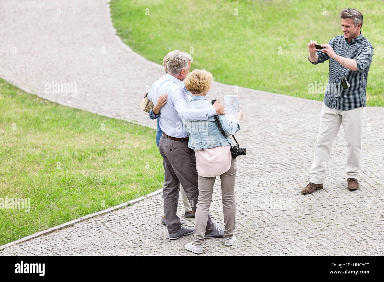 High angle view of man photographing friends at park Banque D'Images