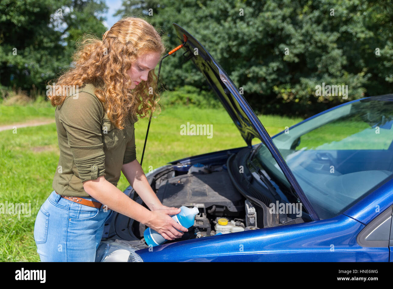 Young caucasian woman voiture remplissage réservoir de liquide lave-glace de pare-brise Banque D'Images