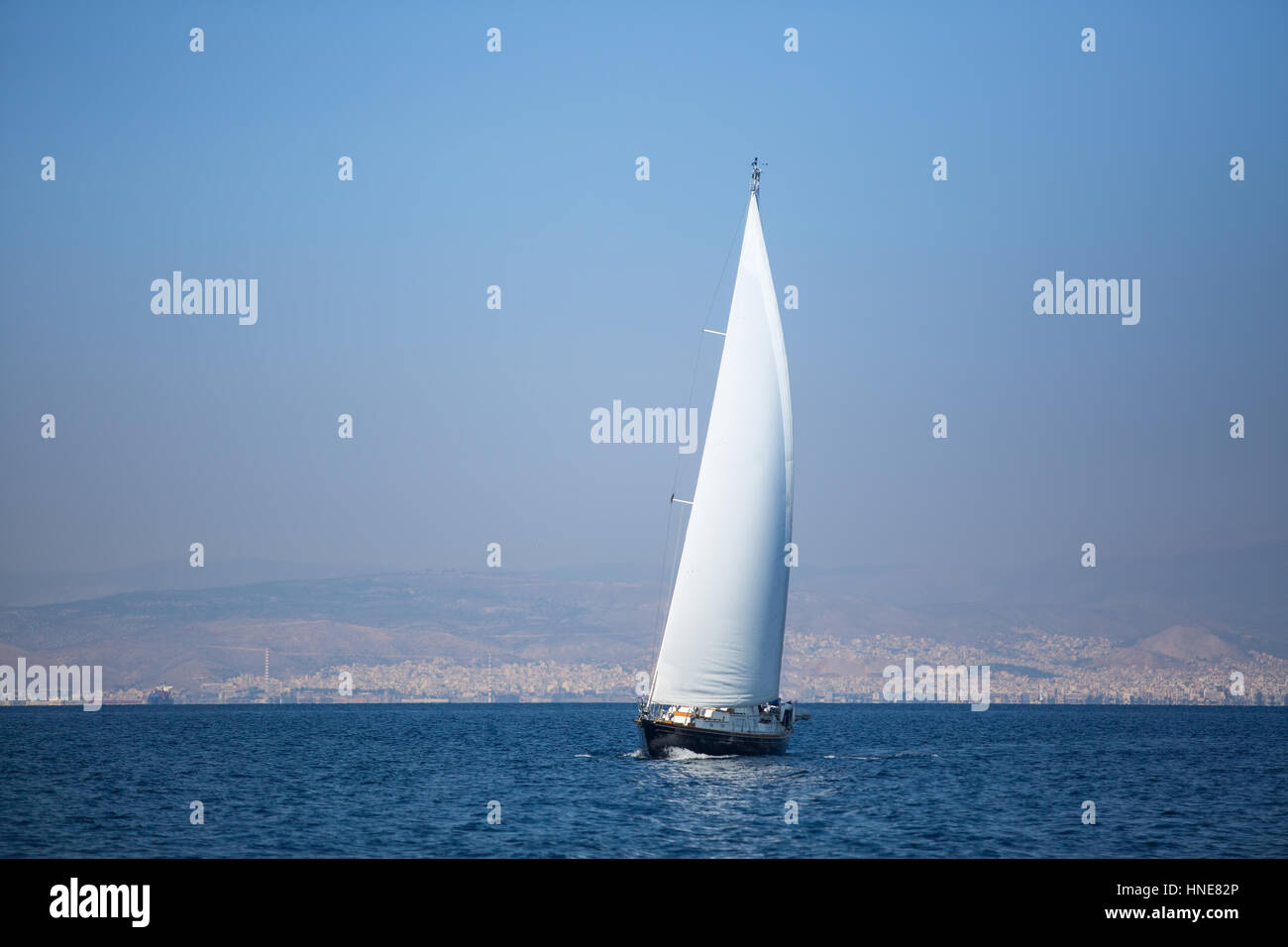 Yacht à voile avec voiles blanches dans la mer près de la côte. Banque D'Images