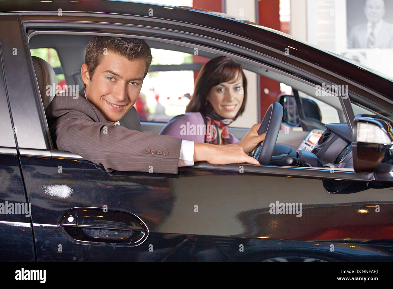 Portrait de jeune couple assis dans une nouvelle voiture à la salle d'exposition Banque D'Images