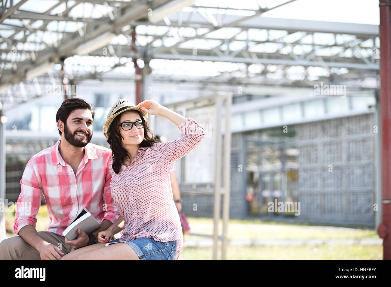 Couple heureux à l'écart tout en étant assis sur un banc à l'ombre Banque D'Images