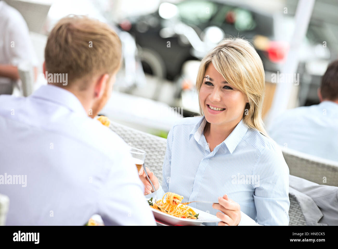Happy businesswoman having food with male colleague at outdoor restaurant Banque D'Images