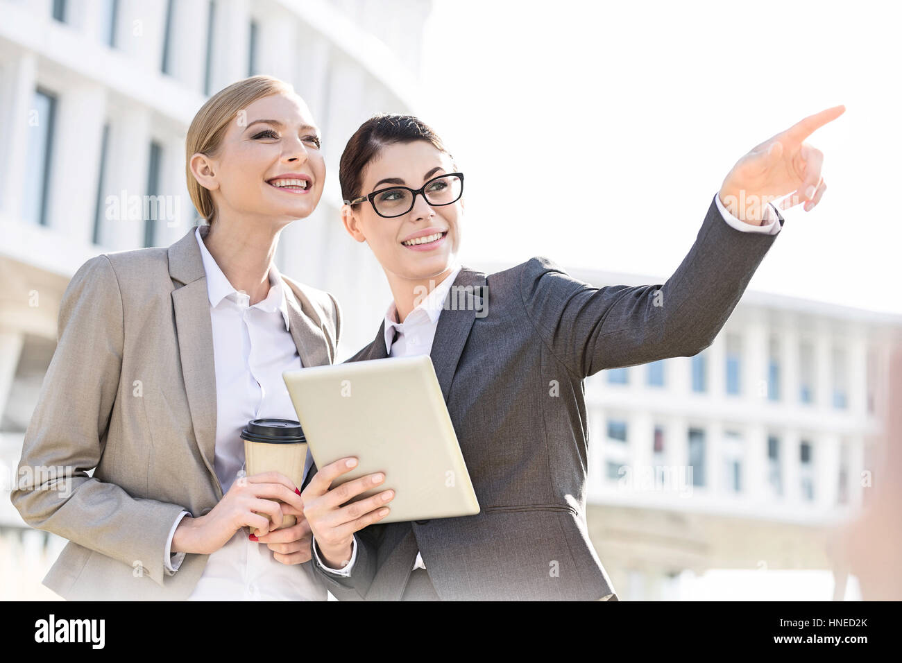 Happy businesswoman montrant quelque chose à collègue lors de l'utilisation de tablet PC Banque D'Images