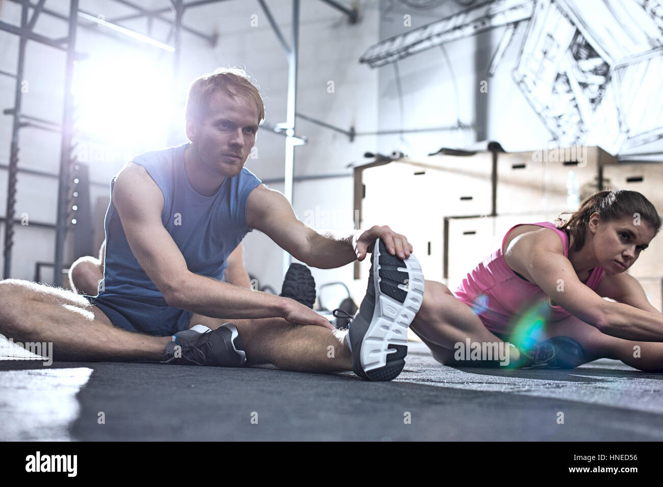 Homme confiant et femme dans l'exercice d'étirement gym crossfit Banque D'Images