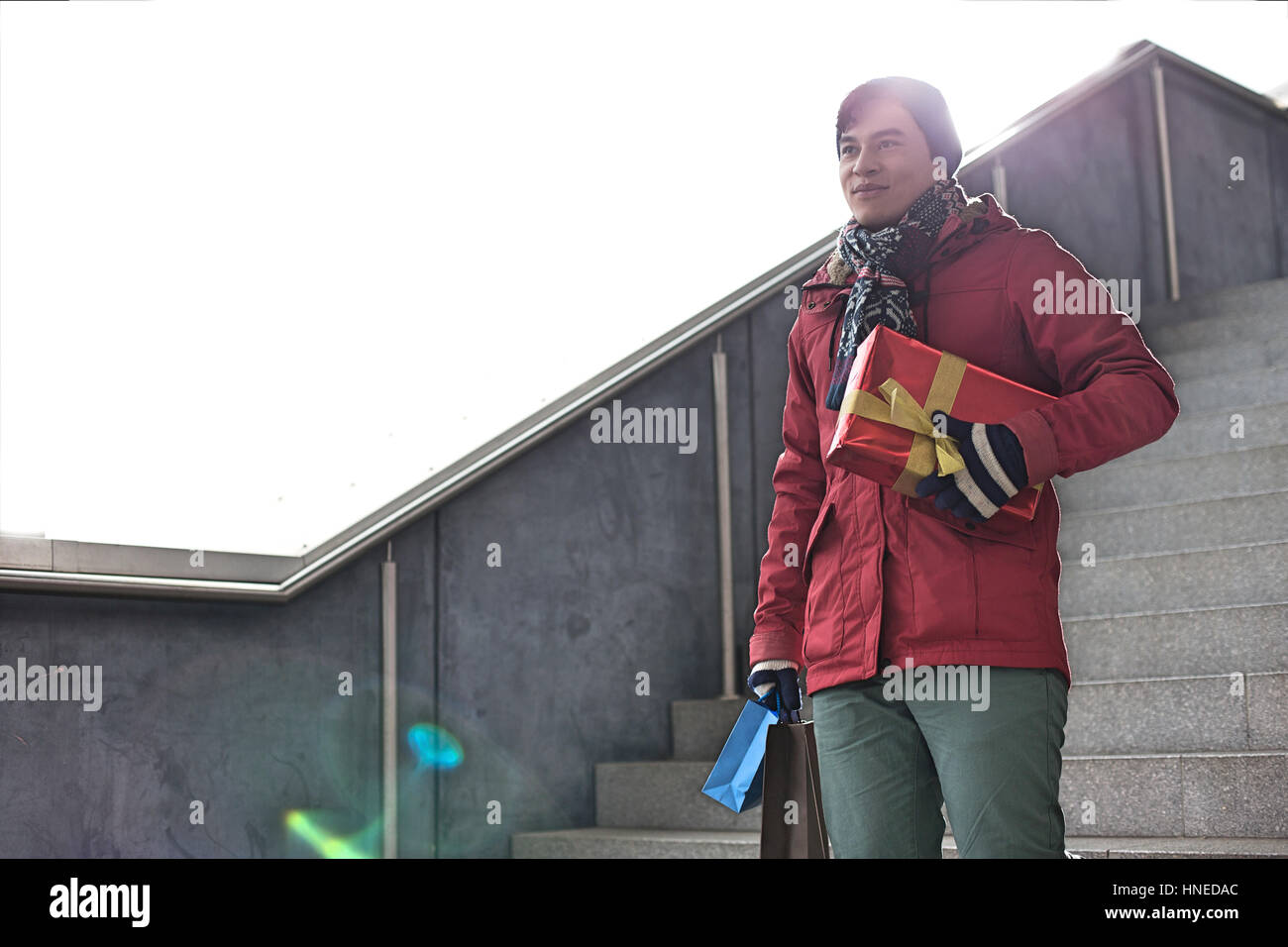 Smiling man holding gifts tout en se déplaçant vers le bas comme suit Banque D'Images