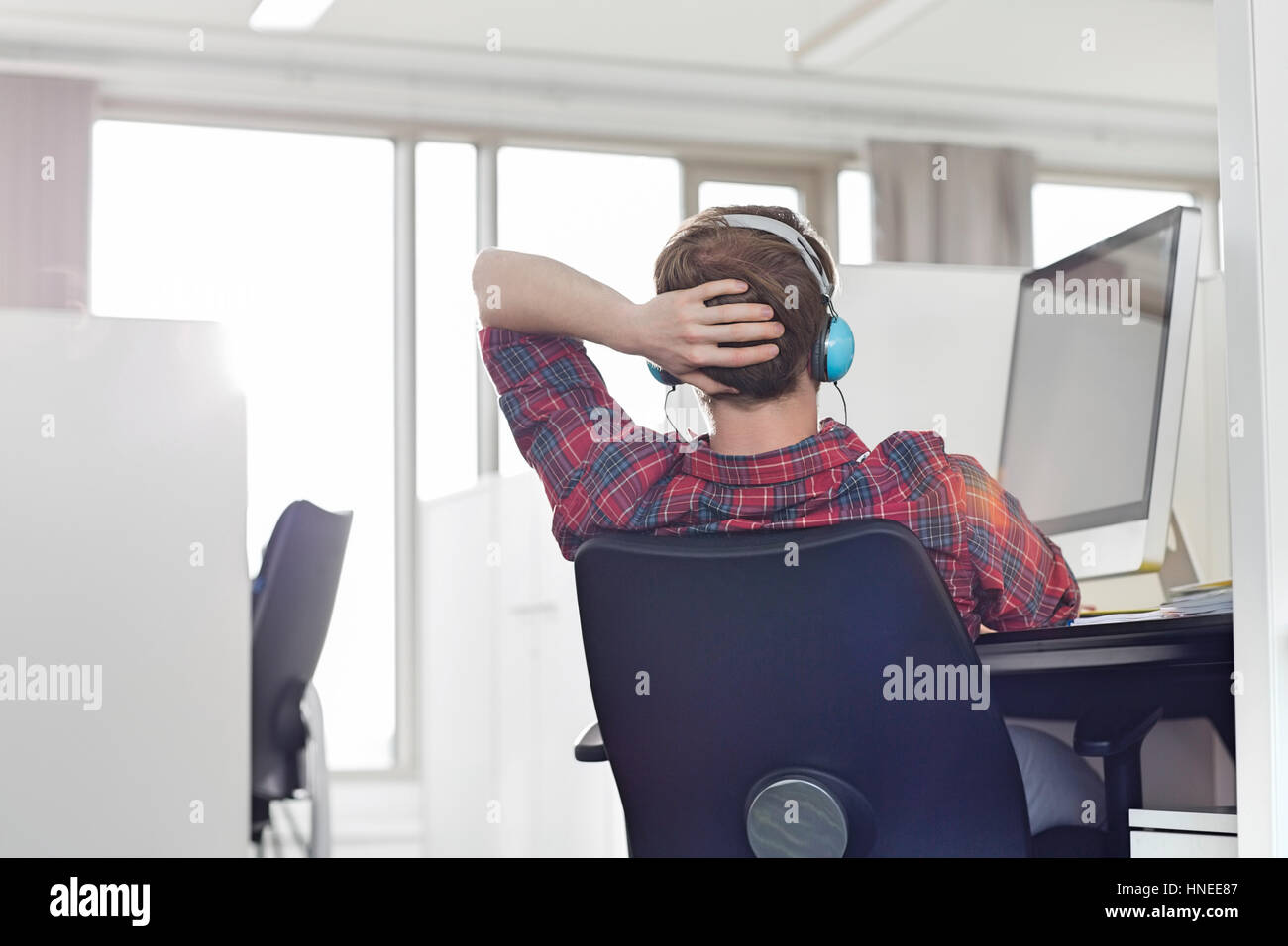 Young businessman wearing headphones at computer desk in office Banque D'Images