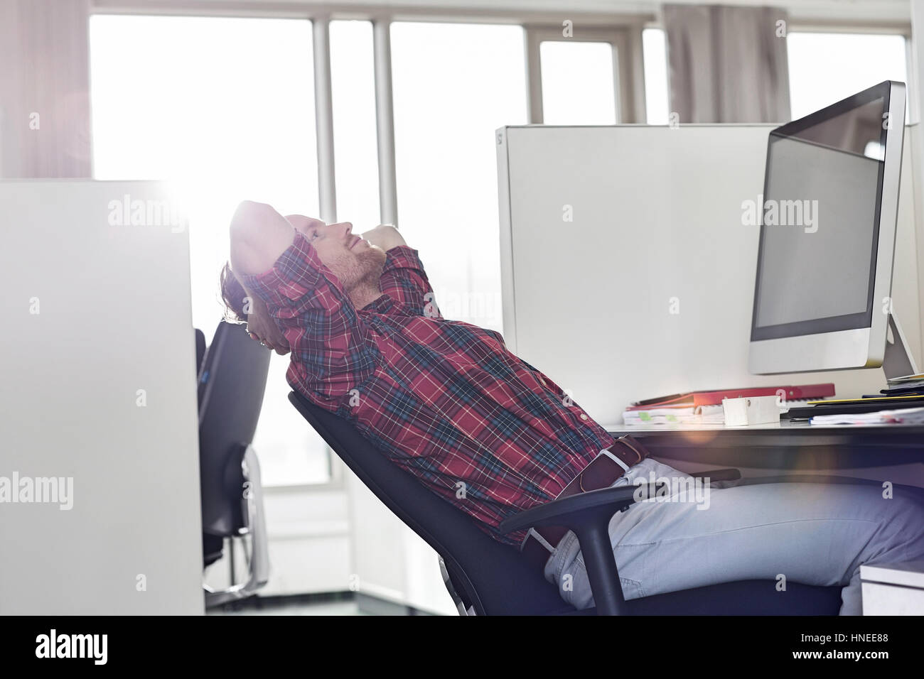 Side view of young businessman relaxing at desk in office Banque D'Images