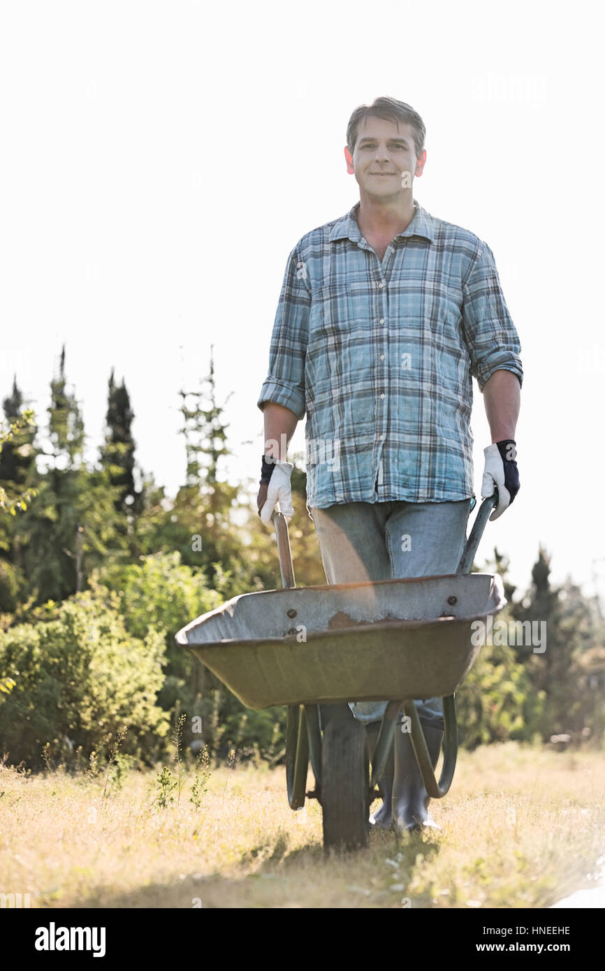 Portrait of male gardener pushing wheelbarrow at garden Banque D'Images