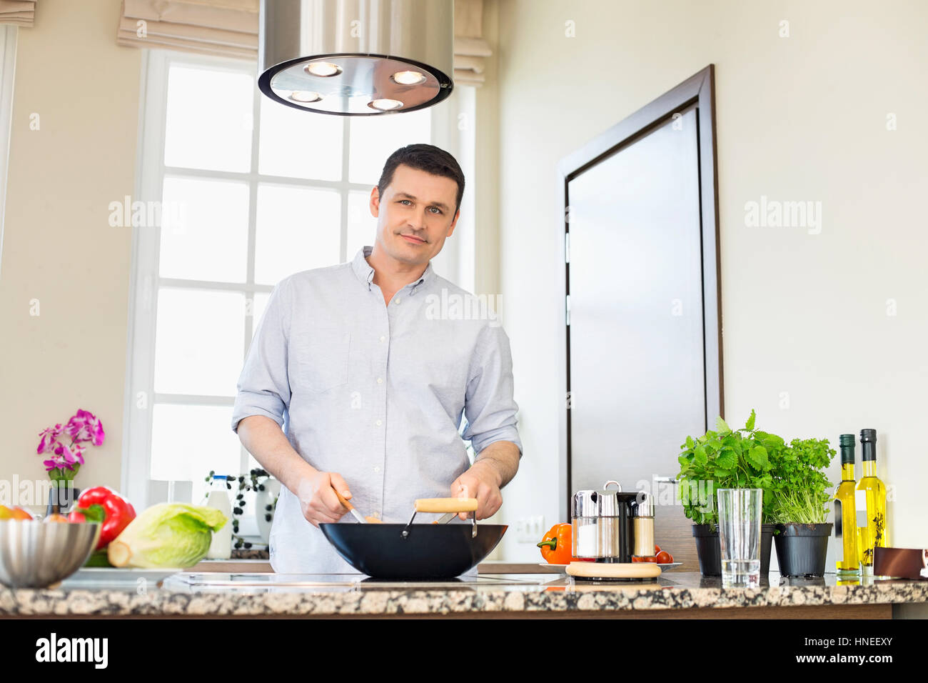 Portrait de l'homme confiant la préparation des aliments dans la cuisine Banque D'Images