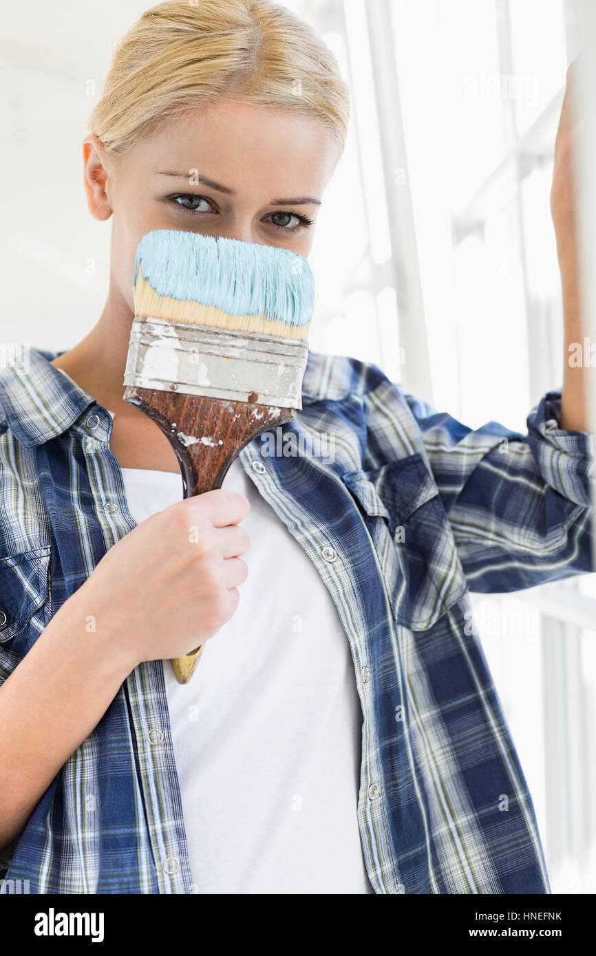 Portrait of woman holding paintbrush in front of face Banque D'Images