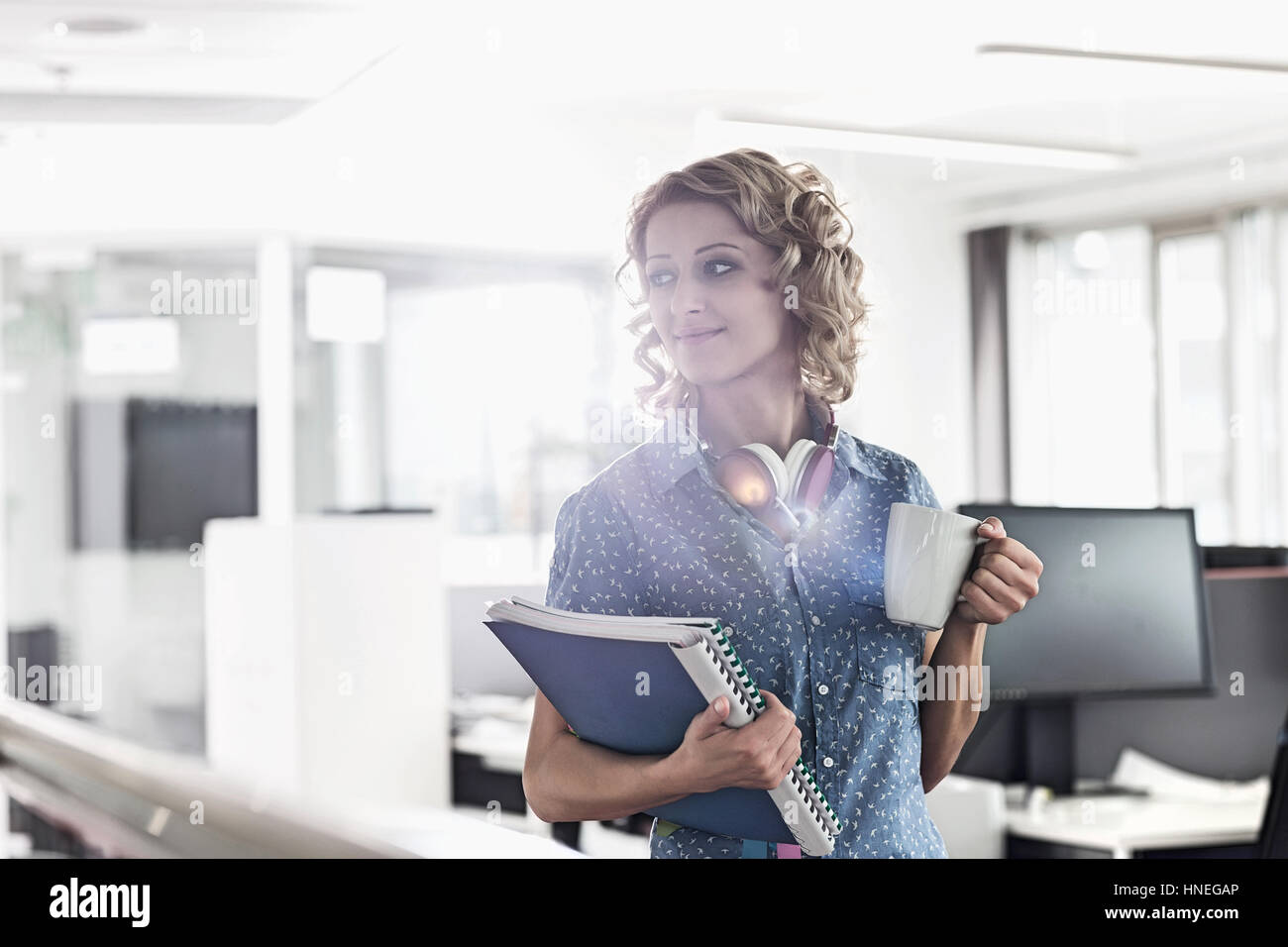 Businesswoman having coffee while holding files in creative office Banque D'Images