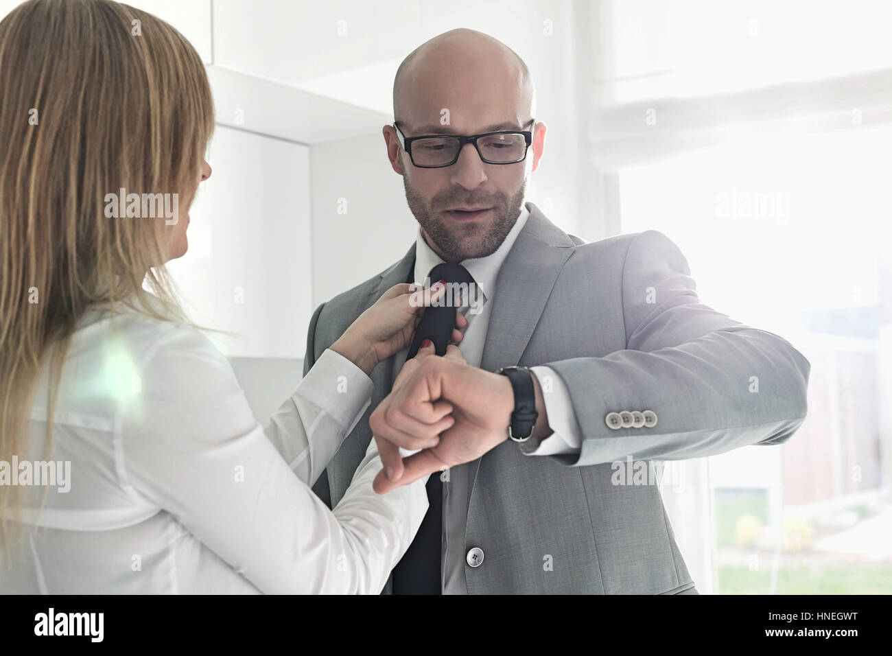 Mid adult businessman contrôle tout en montre-bracelet femme ajustant sa cravate à la maison Banque D'Images