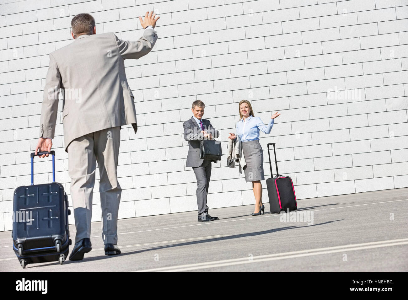 Vue arrière du businessman carrying assurance en agitant la main à des collègues Banque D'Images