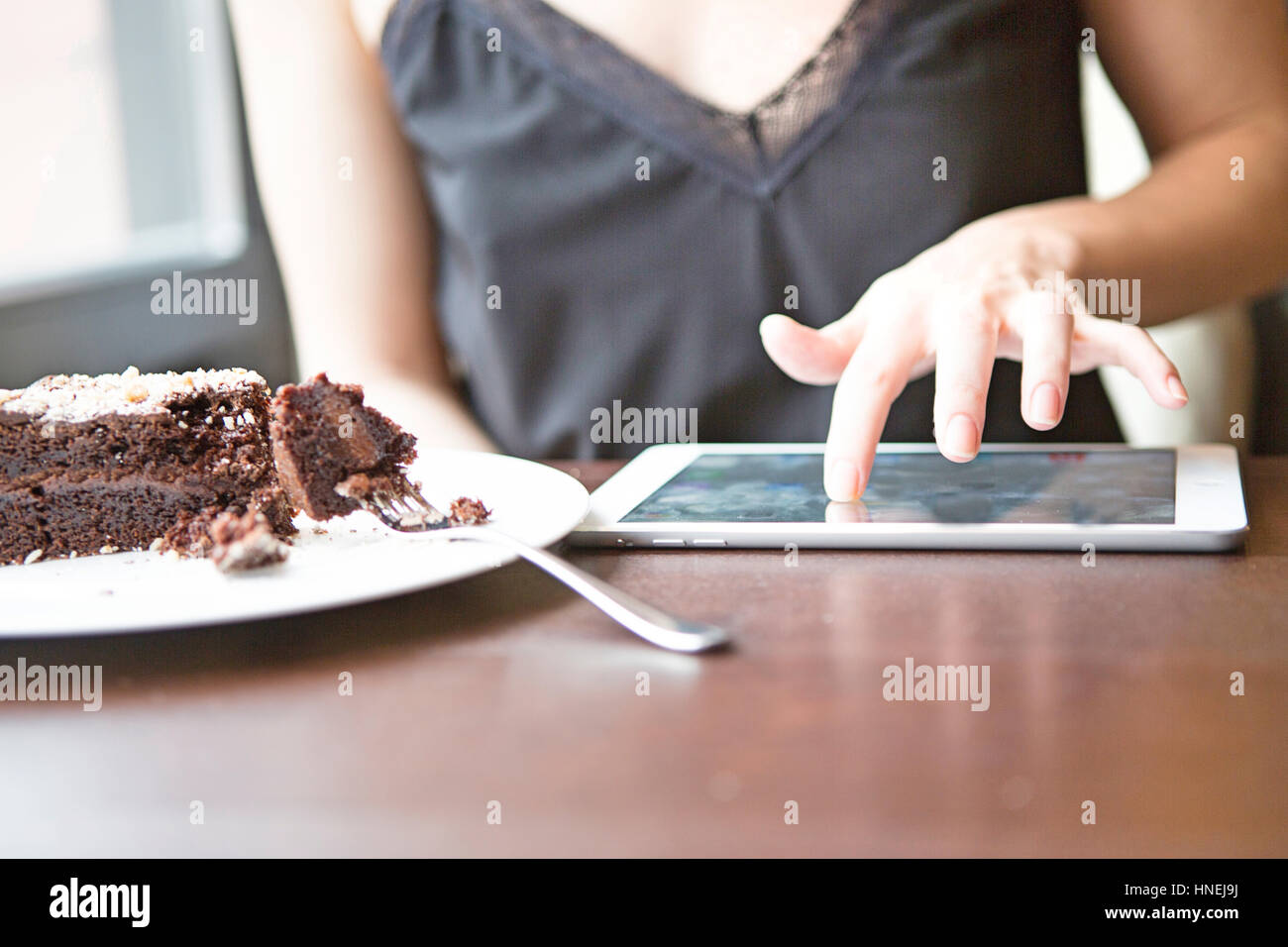 Portrait of woman using tablet PC par pastry in cafe Banque D'Images