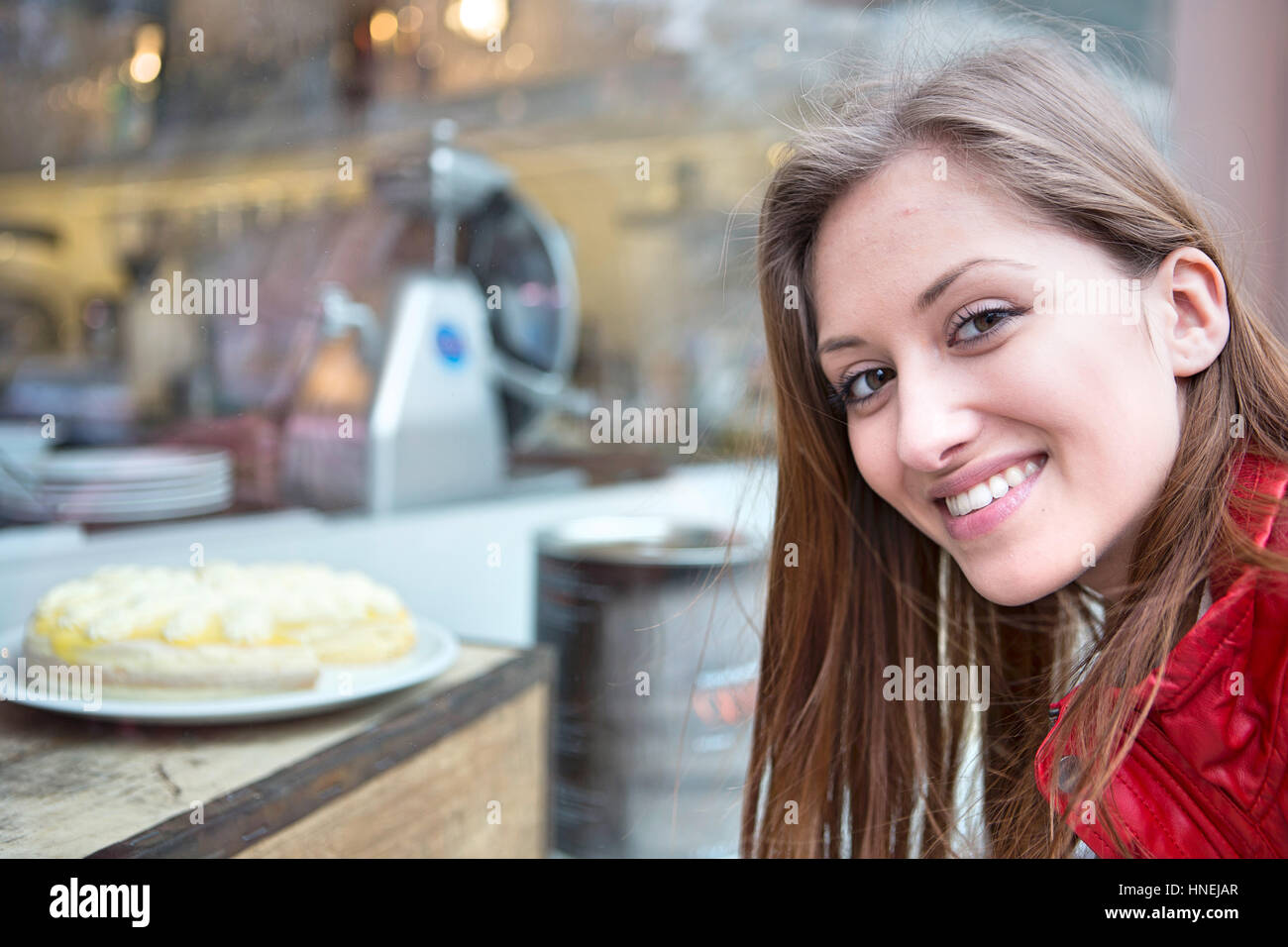 Portrait de femme heureuse par display cabinet in cafe Banque D'Images