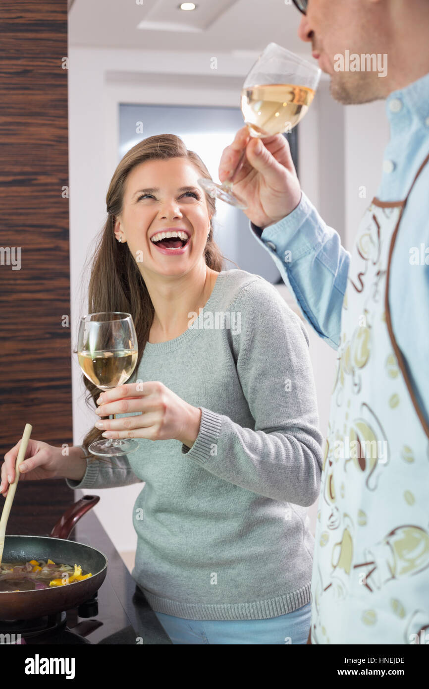 Cheerful couple having wine pendant la cuisson dans la cuisine Banque D'Images