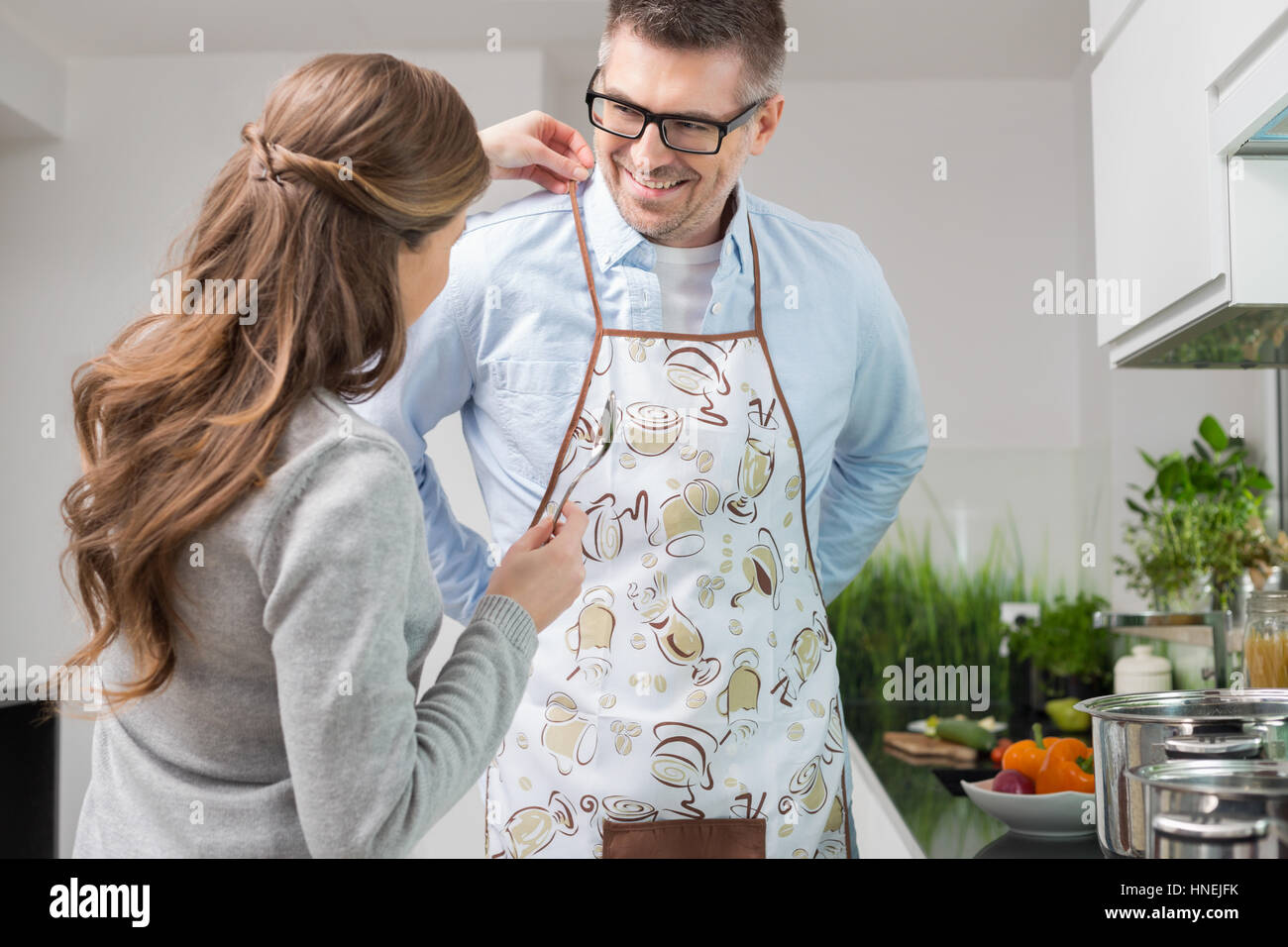 Femme Homme aidant à mettre sur un tablier de cuisine en Banque D'Images