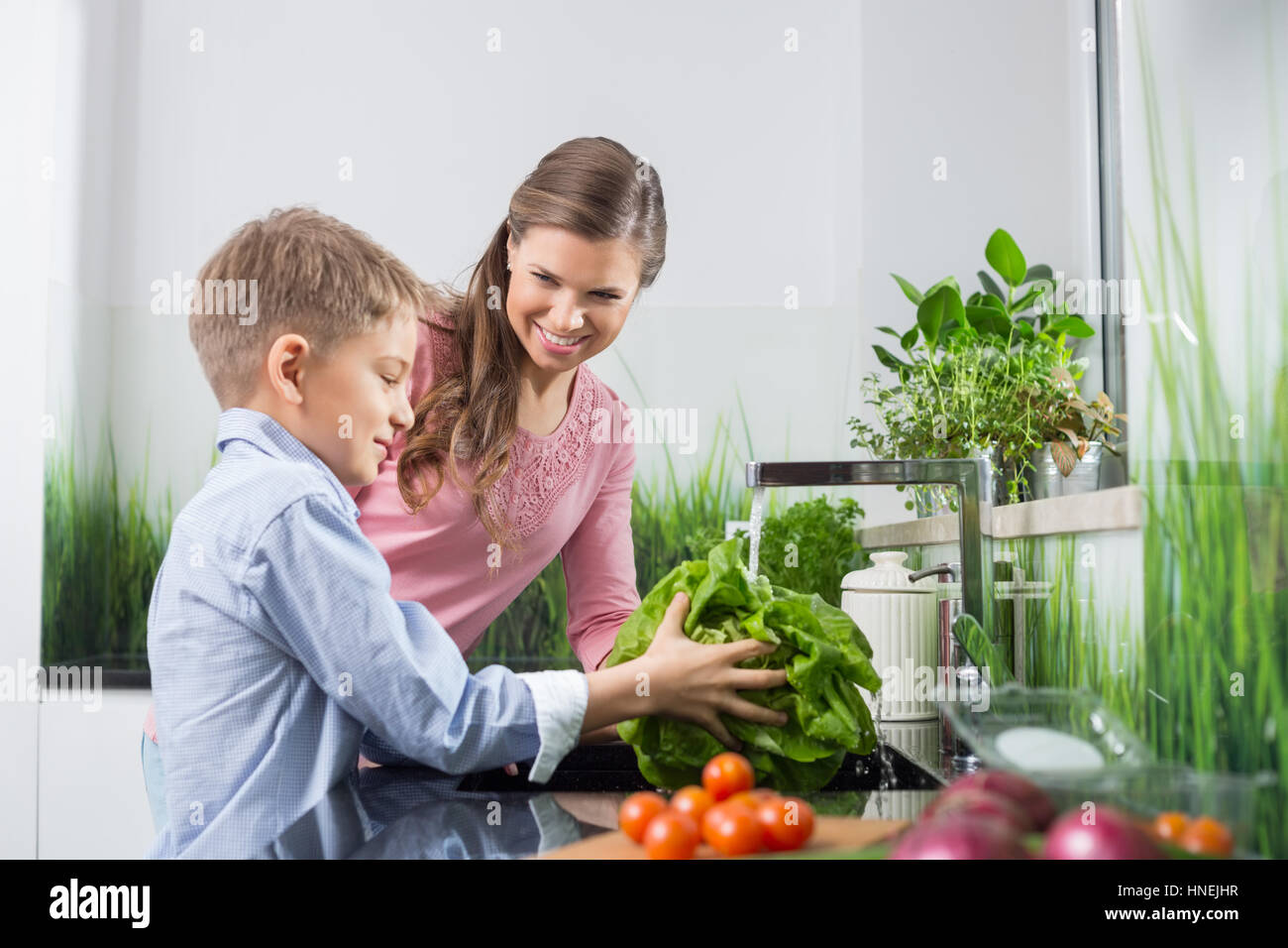 Heureuse fête à fils à laver les légumes dans la cuisine Banque D'Images
