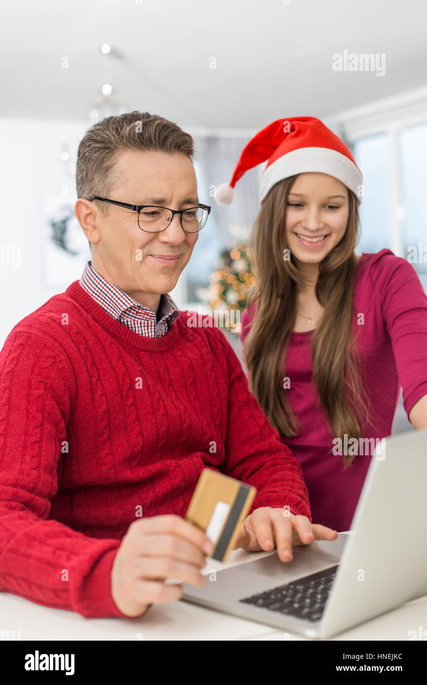 Smiling father and daughter shopping en ligne à la maison durant les fêtes de Noël Banque D'Images