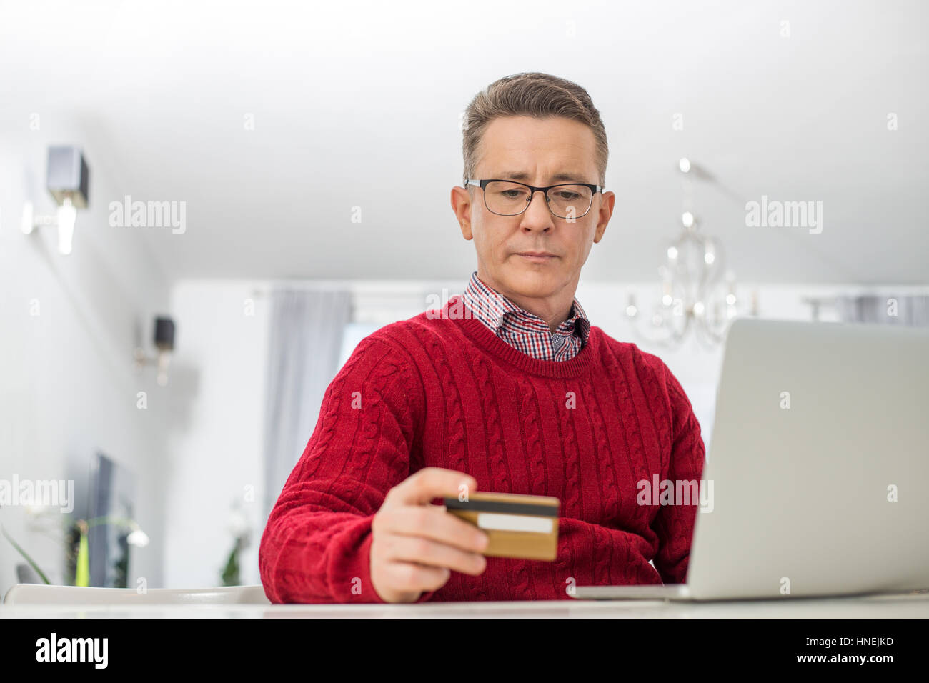 Homme mûr à l'aide d'un ordinateur portable et une carte de crédit pour faire des achats en ligne à la maison Banque D'Images