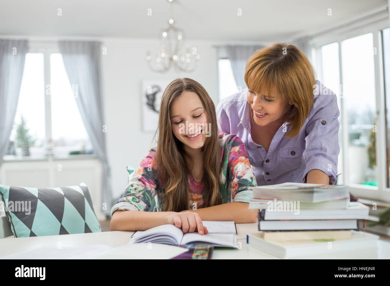 Smiling mother aider sa fille à faire ses devoirs à la table Banque D'Images