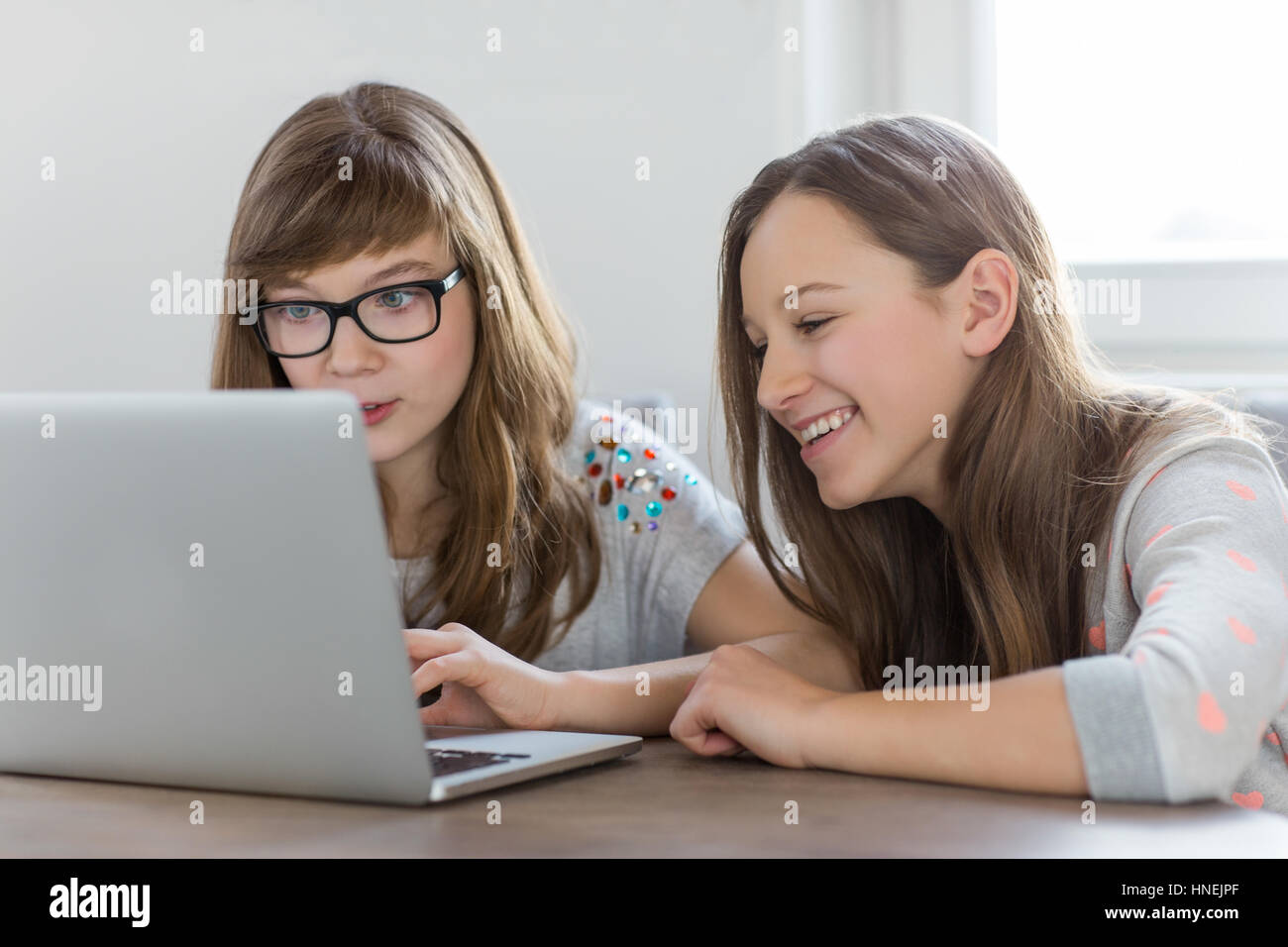 Sœurs using laptop together at home Banque D'Images
