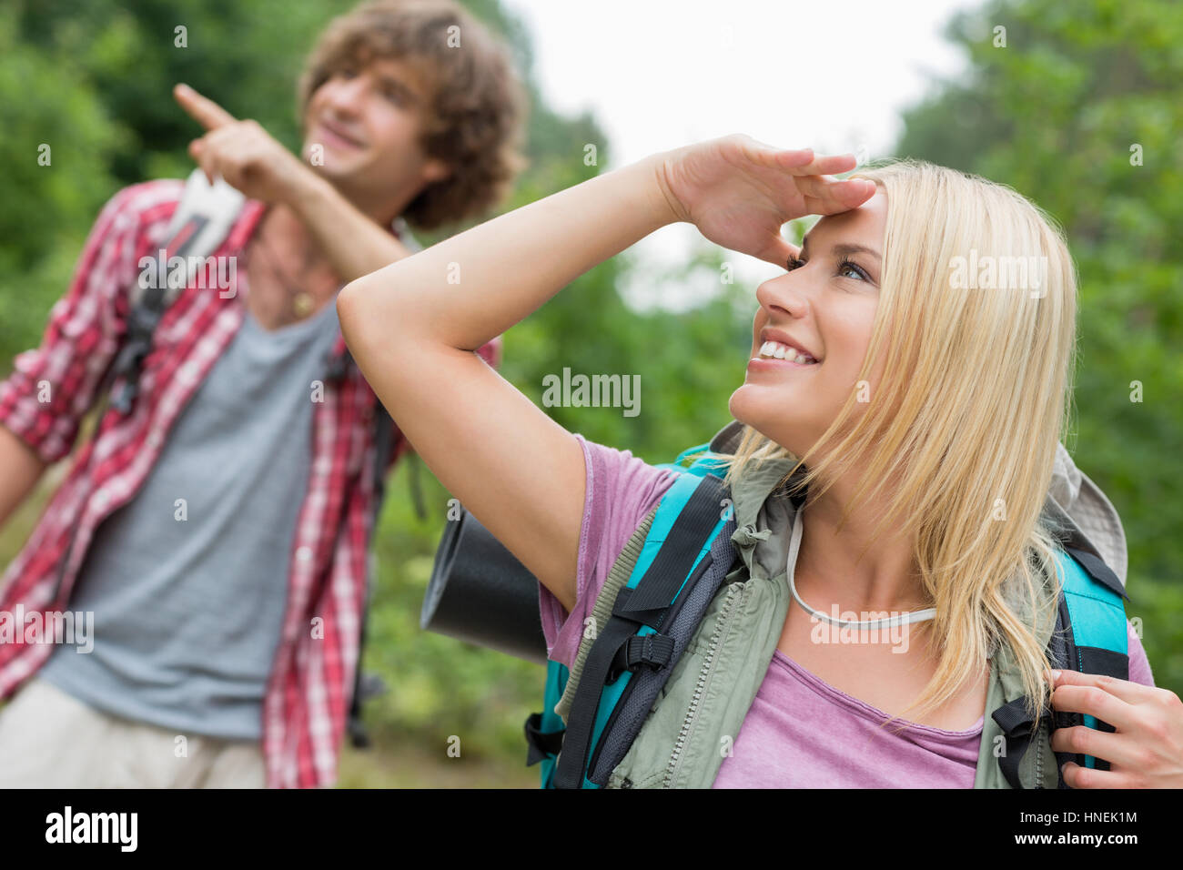 Femme à la voiture tandis que l'homme backpacker montrant quelque chose dans la forêt Banque D'Images