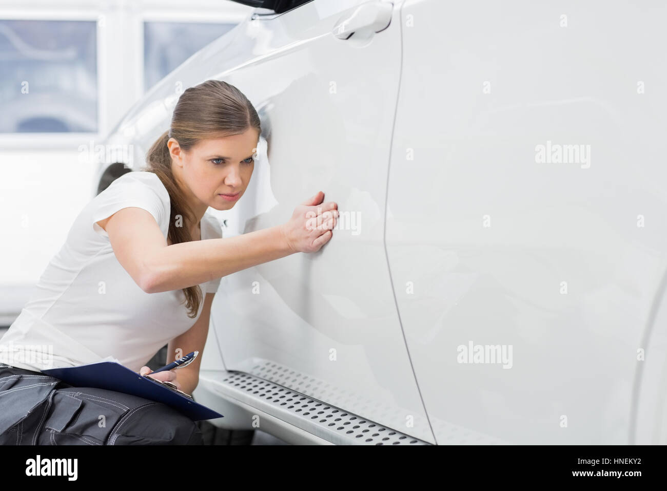 L'examen de technicien d'entretien d'une femme à l'atelier d'automobile Banque D'Images